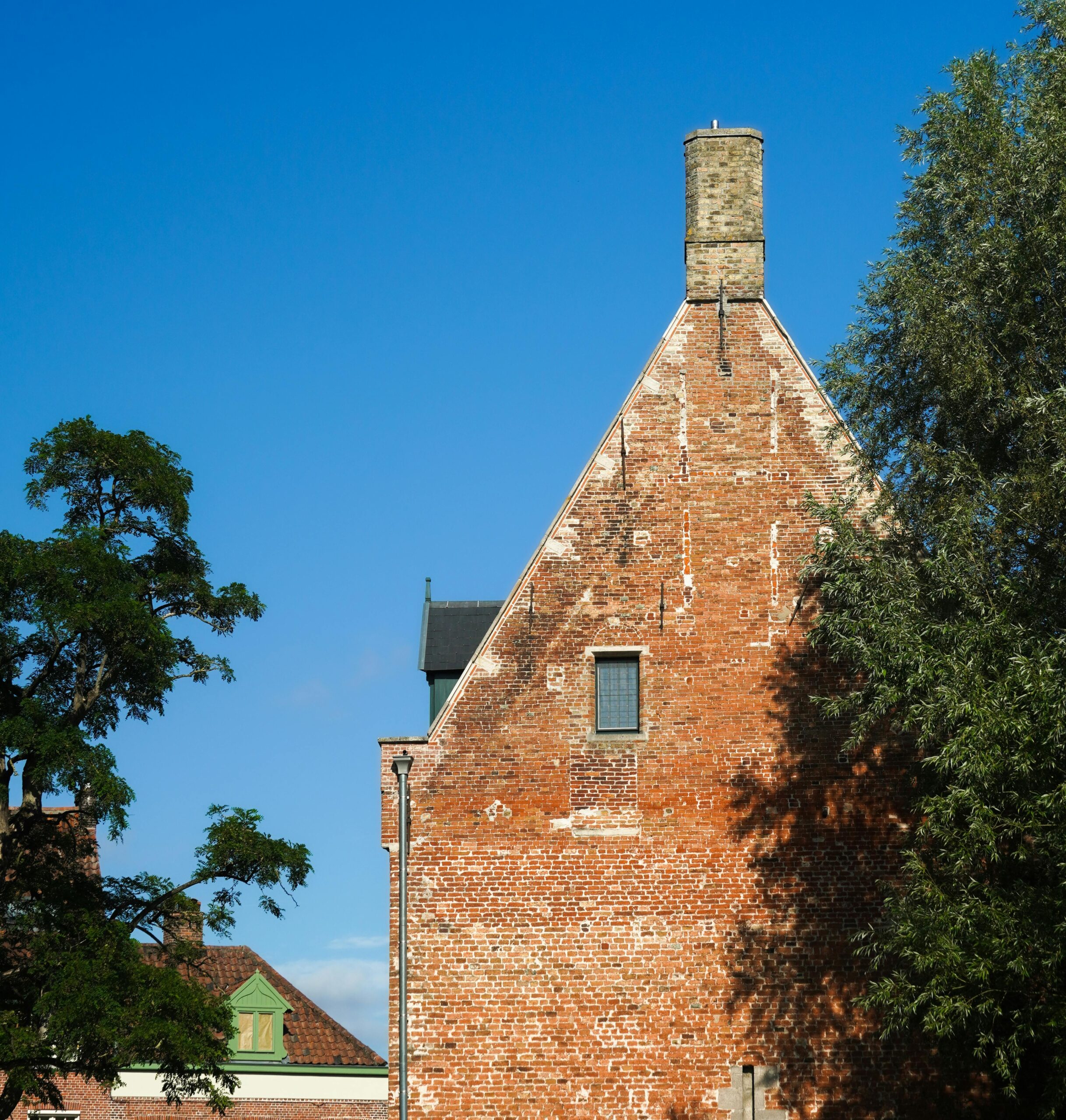 Charming red brick building with greenery on a sunny day in Brugge, Belgium.